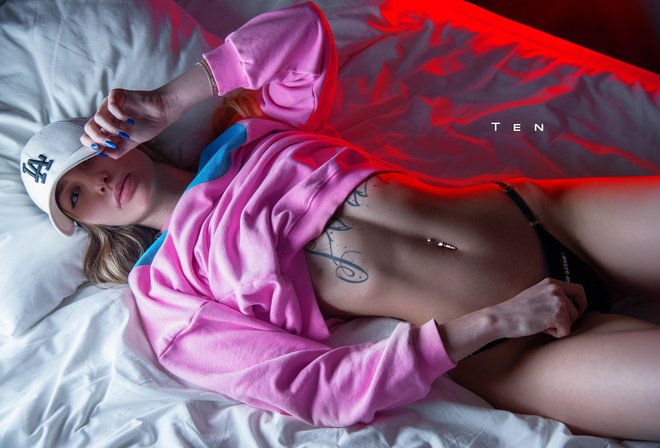 women, alexander ten, baseball cap, black panties, tattoo, in bed, pink lipstick, pink sweater, blue nails, belly, pierced navel, top view, hips