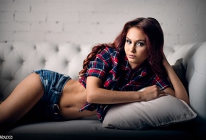 women, tanned, jean shorts, plaid shirt, belly, couch, pink lipstick, dyed hair, wall, bricks