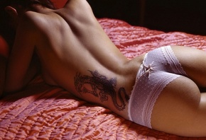 Девушка на кровати на  в розовых трусиках, на пояснице тату, обои для рабоч ...