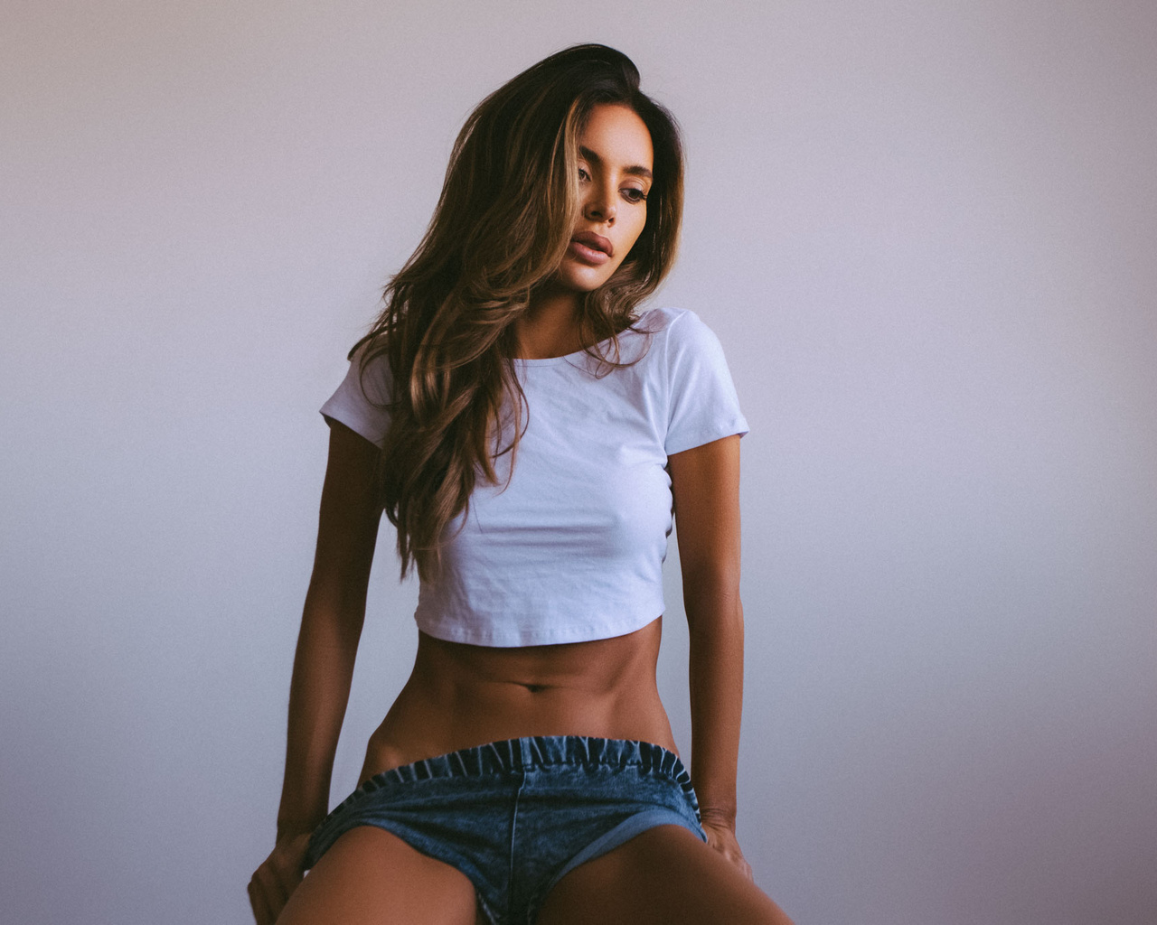 women, t-shirt, tanned, belly, jean shorts, sitting, simple background, looking away