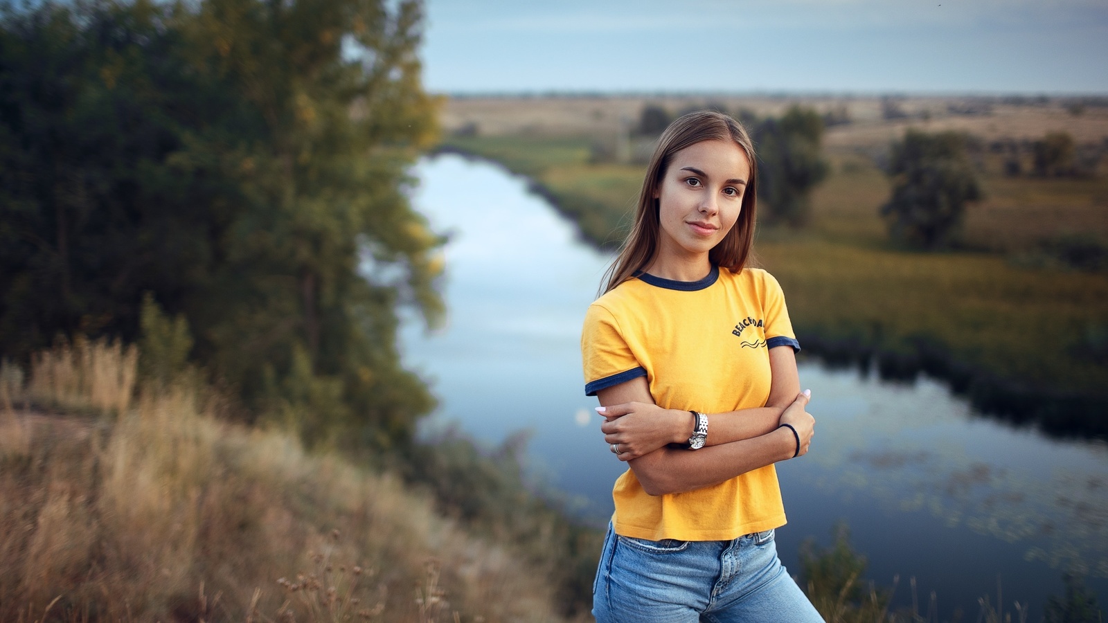 women, yellow t-shirt, river, nature, jeans, watch, arms crossed, sky, women outdoors, smiling