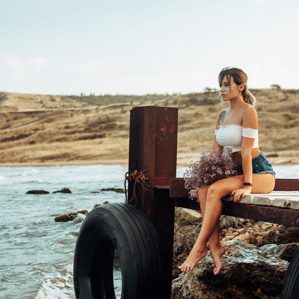 women, brunette, sea, women outdoors, jean shorts, pier, sitting, red nails, tattoo, sky, watch, tires, bare shoulders, looking away