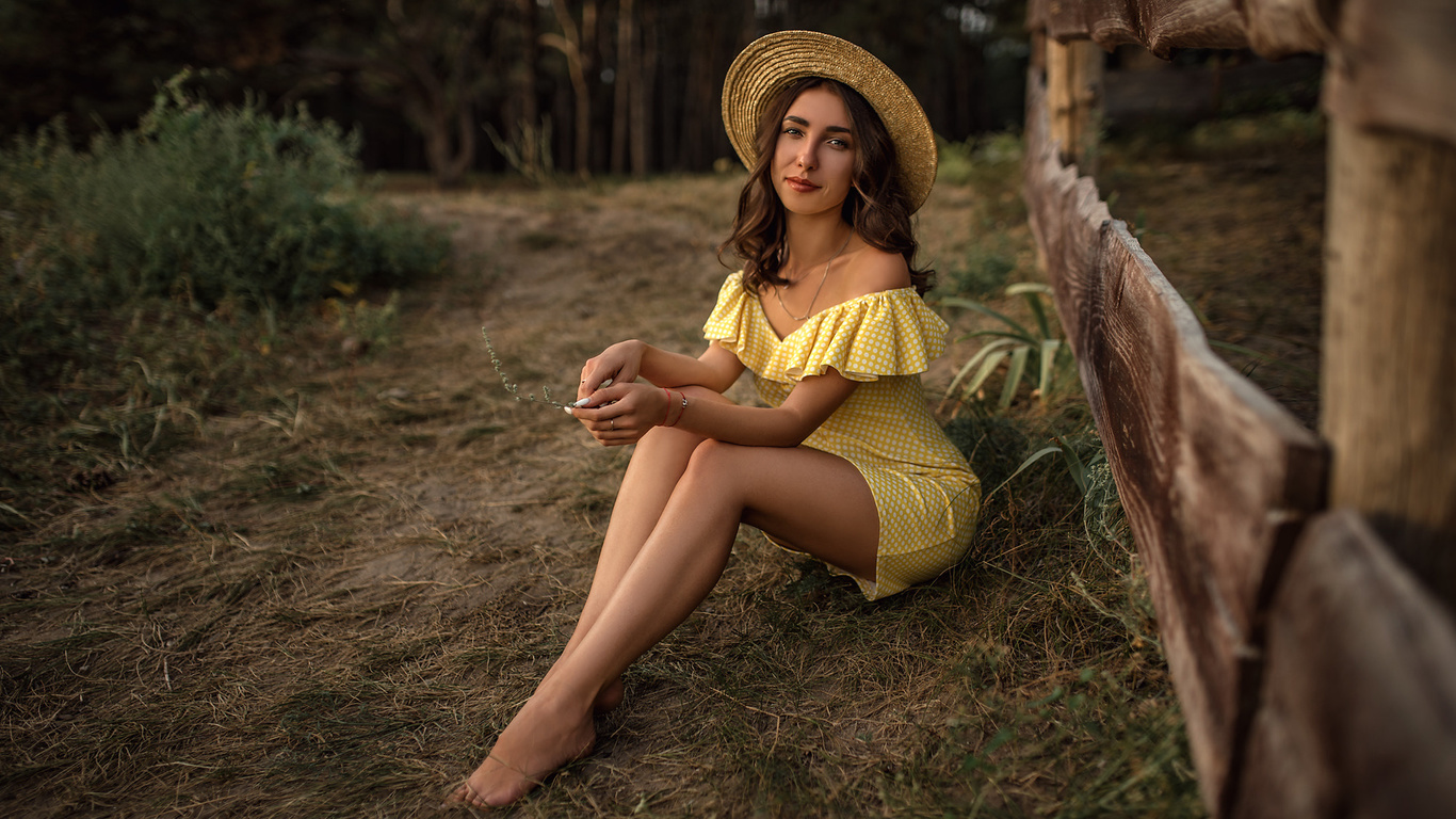 women, skinny, yellow dress, women outdoors, brunette, polka dots, hat, fence, necklace, smiling, trees, sitting