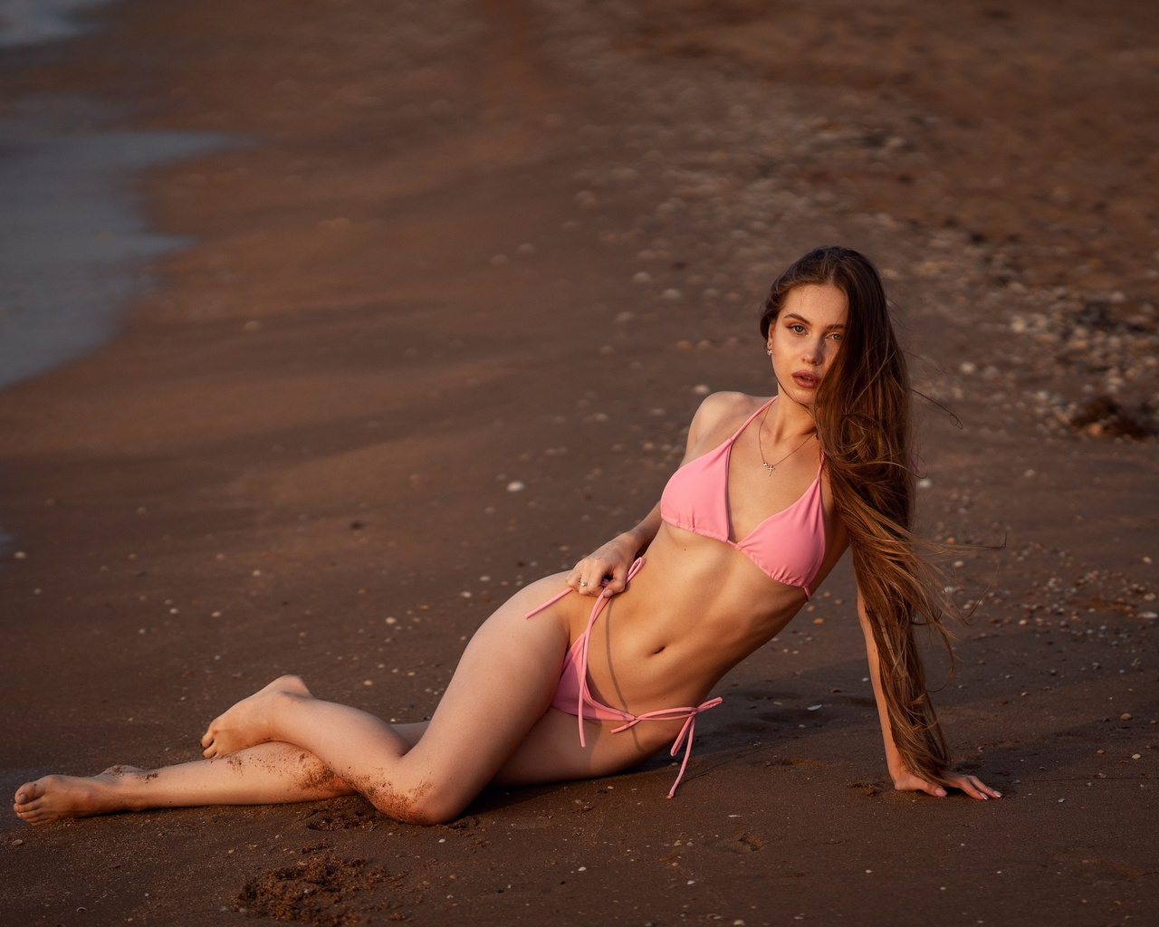 women, pink bikini, long hair, sand, sea, belly, ribs, crucifix necklace, women outdoors, hips, pink nails, sand covered body, sitting