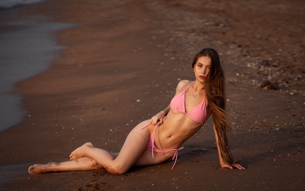 women, pink bikini, long hair, sand, sea, belly, ribs, crucifix necklace, women outdoors, hips, pink nails, sand covered body, sitting