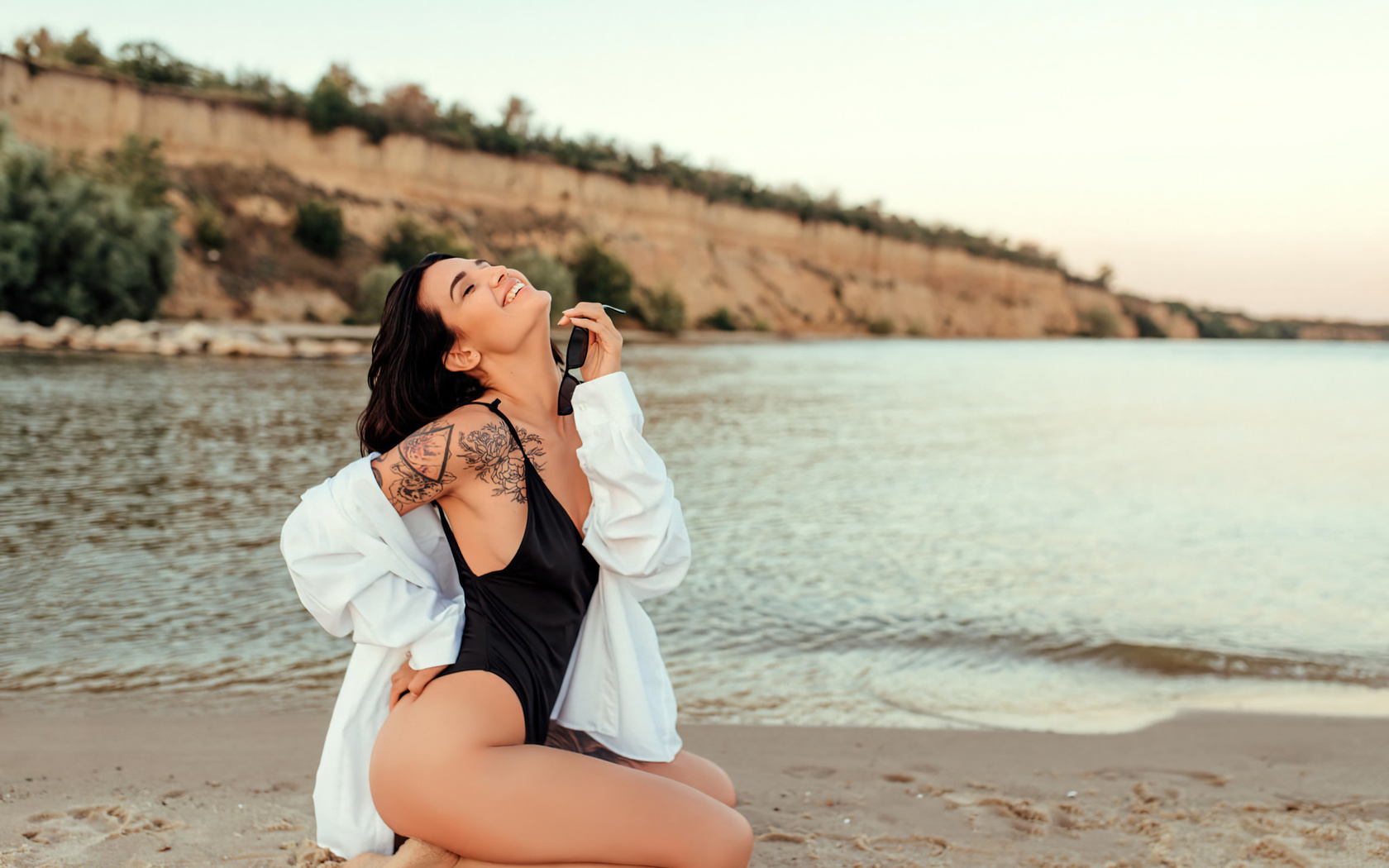 women, kneeling, sand, sunglasses, smiling, one-piece swimsuit, sea, tattoo, white shirt, women outdoors, closed eyes