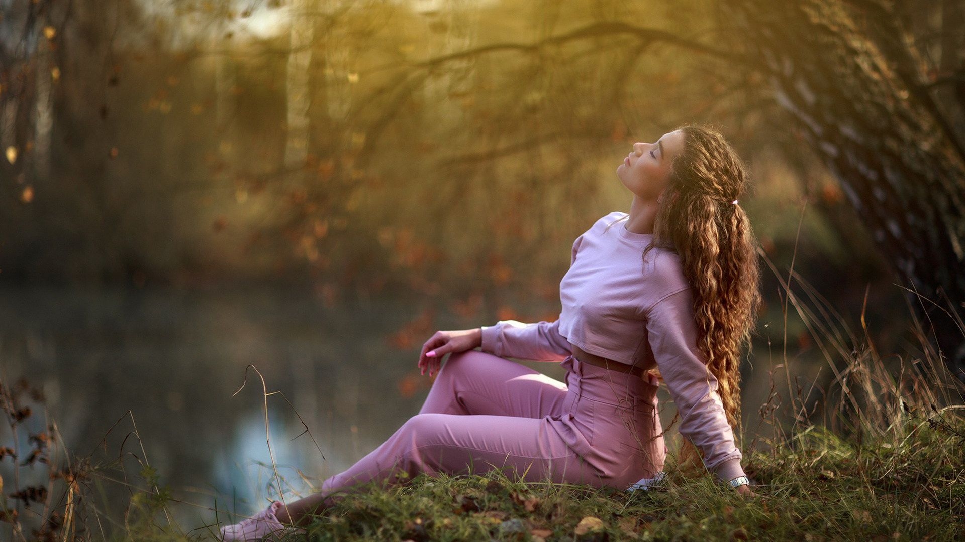 women, model, brunette, women outdoors, lake, nature, curly hair, wavy hair, sitting, sweater, pants, closed eyes, sneakers, trees, grass